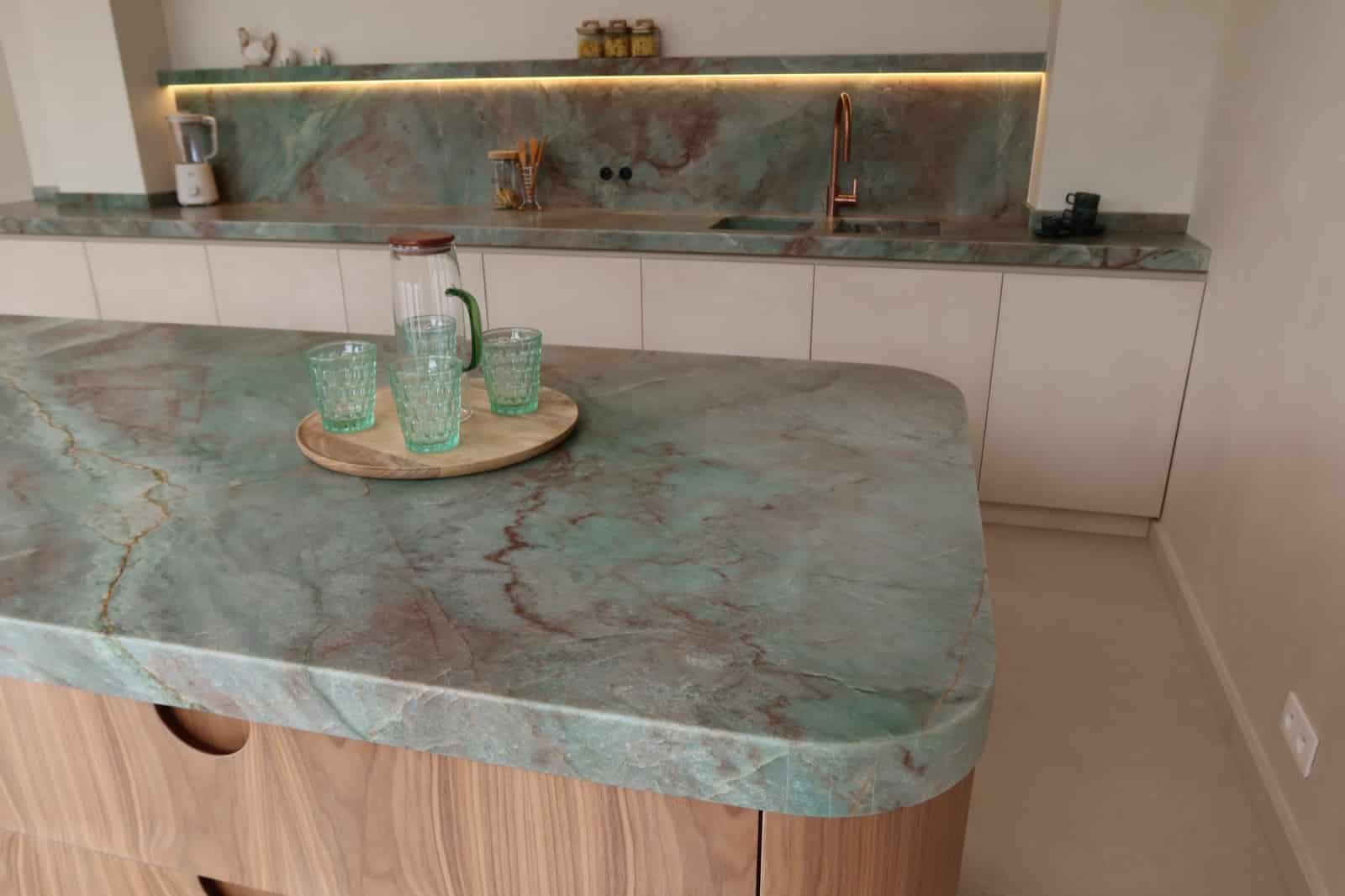 Keuken met een groen marmeren werkblad op een eiland met houten fronten