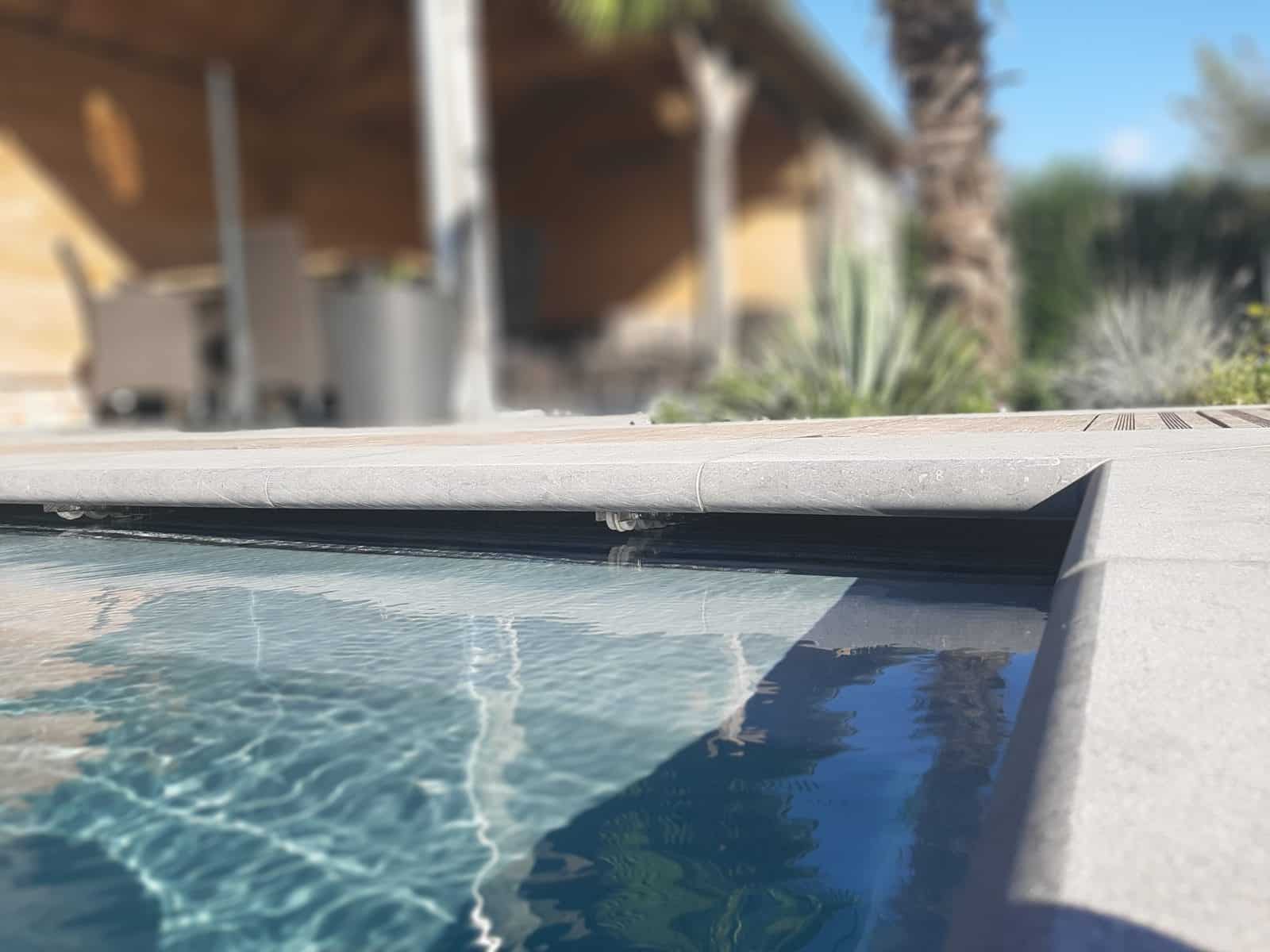 Natuurstenen zwembadboord aan een terras met overkapping